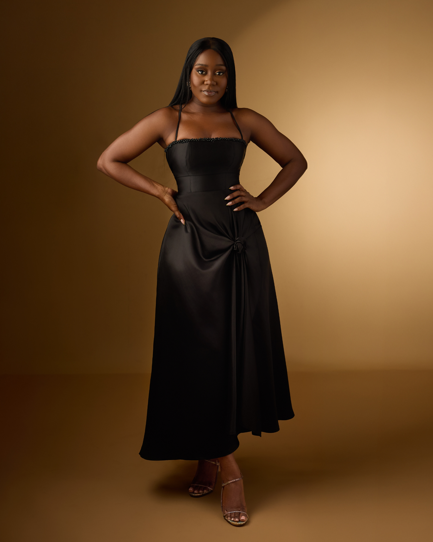 An elegant black satin midi dress with a beaded neckline and knotted waist detail. The Luna Knotted Dress is timeless and feminine.